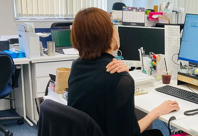 デスクワークの肩こりに悩んでいる女性の写真